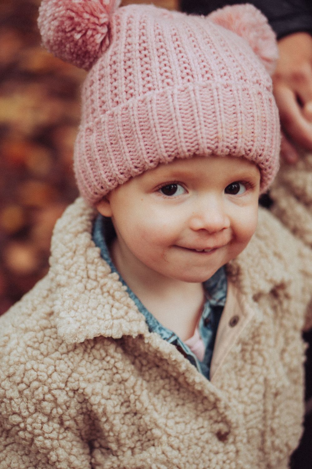 A portrait of a little girl all wrapped up in her winter clothes, fluffy coat and pink hat.