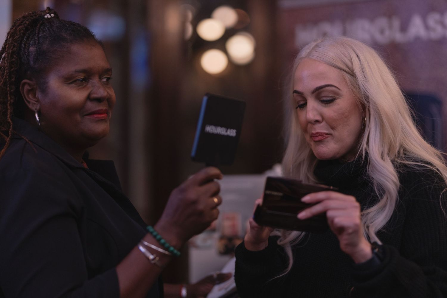 Two people examining mobile devices at an evening social event.