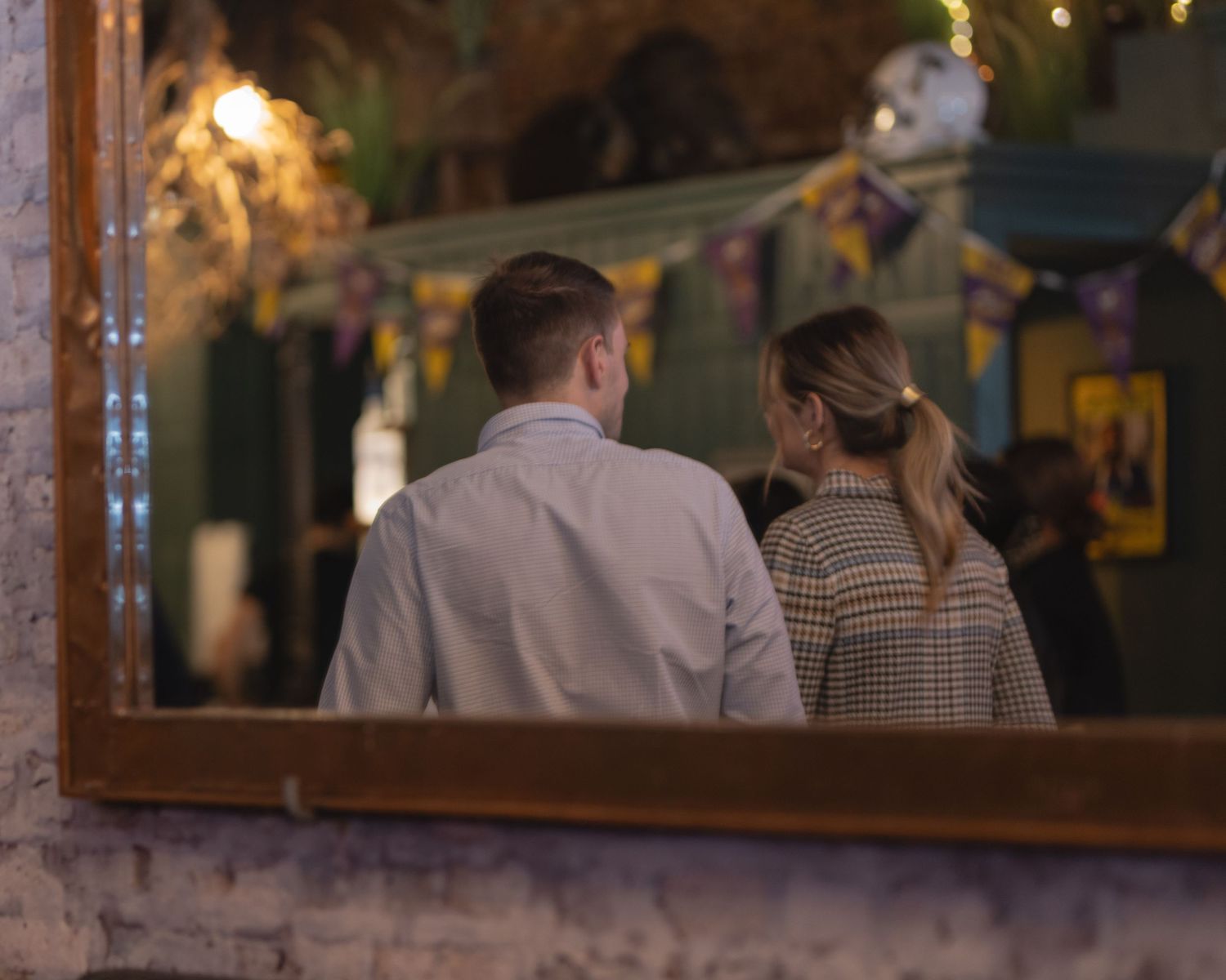 Couple viewed from behind looking at holiday decorations through a reflective window display.