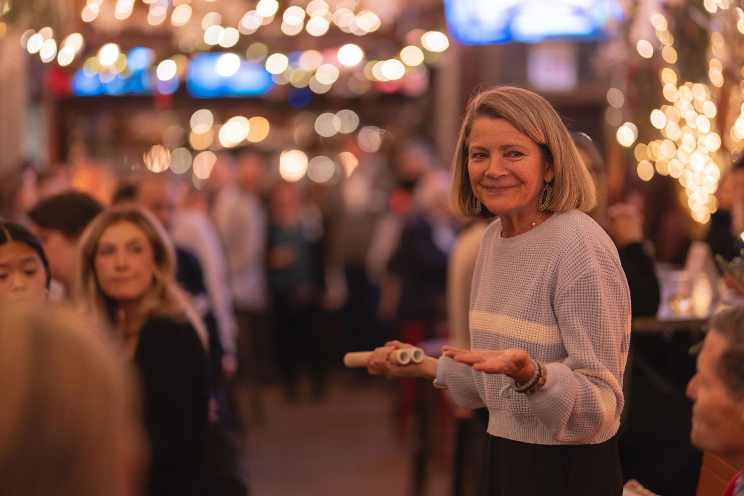 Social gathering in festive venue with twinkling lights and holiday decorations.