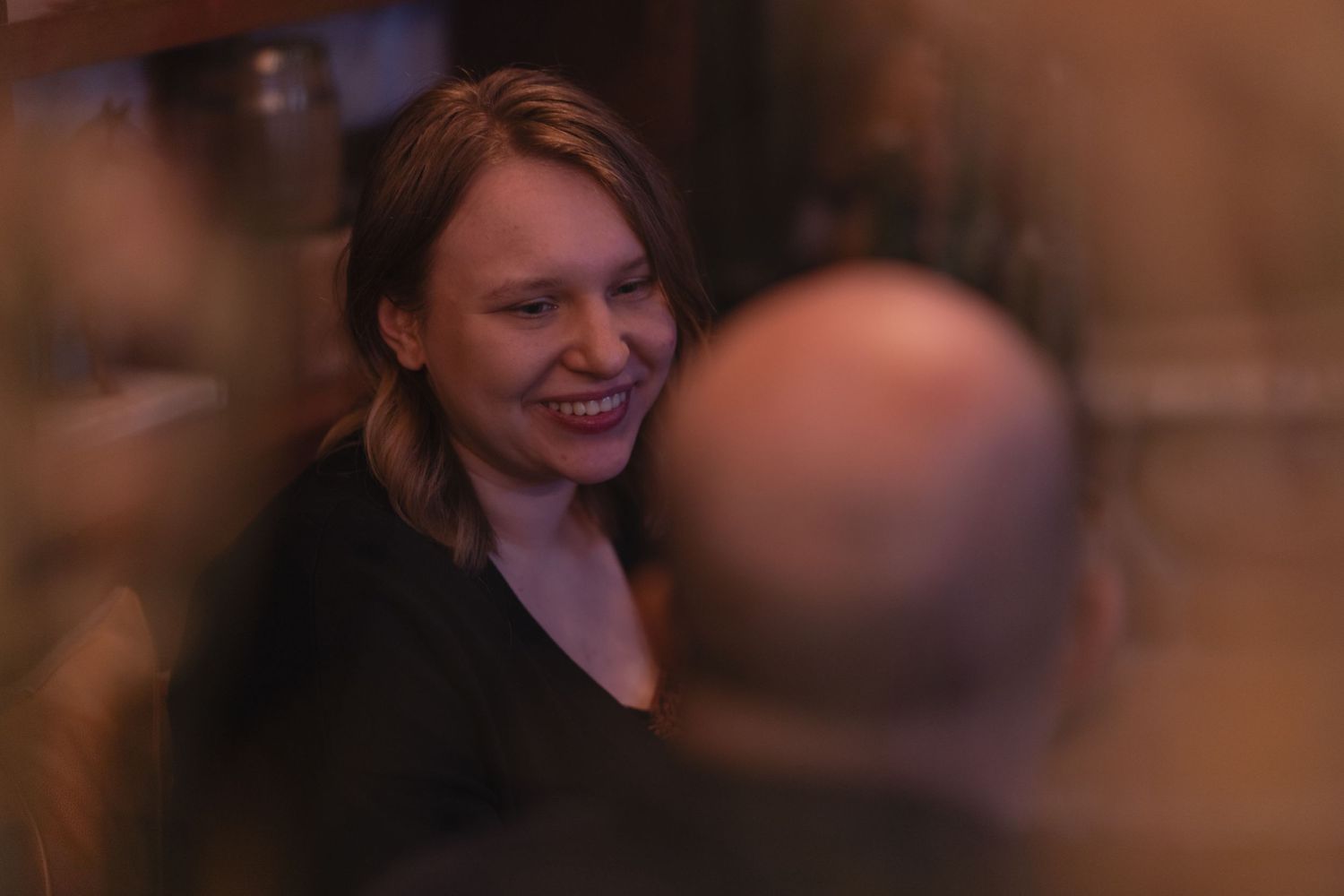 Dimly lit social gathering with attendees engaged in conversation.