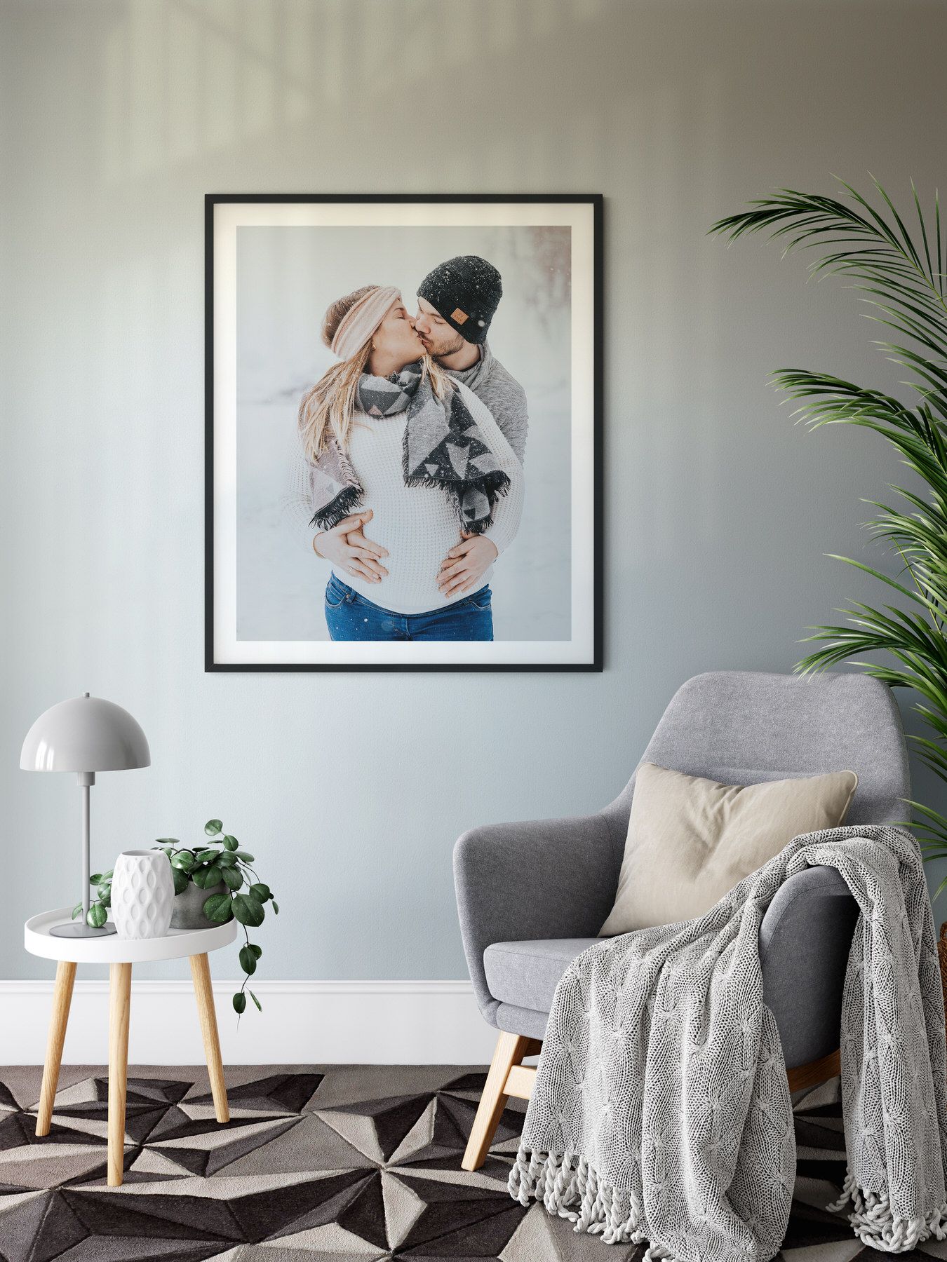 Framed black and white photograph displayed in a modern living room with gray armchair and geometric rug.