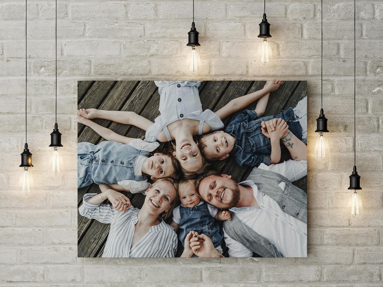 Familienporträt auf weißer Backsteinmauer, beleuchtet von hängenden Pendelleuchten.