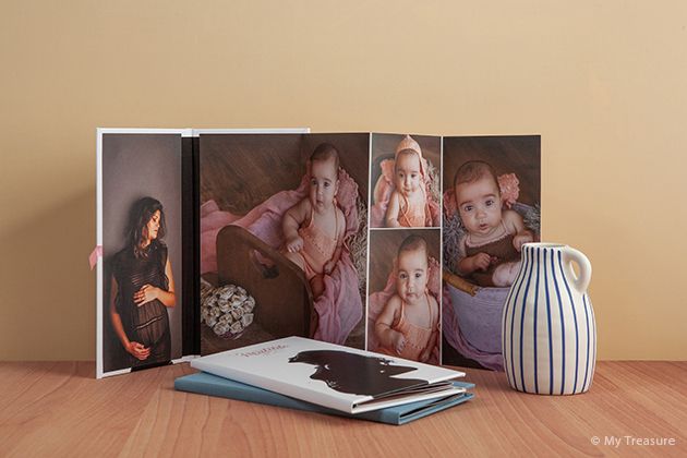 Professional photo album display with decorative vase on wooden table surface.