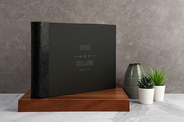 Luxury black photo album with embossed texture displayed with modern vases and plants.