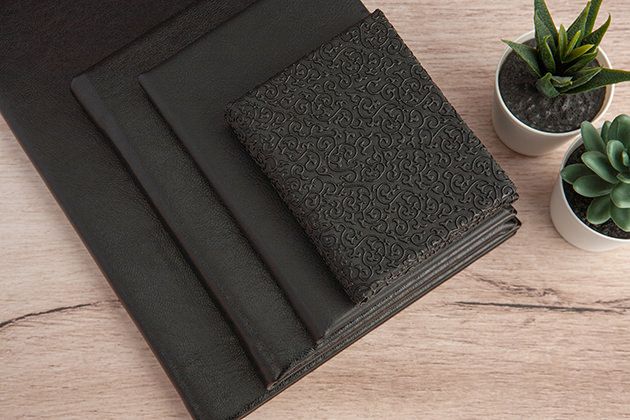 Elegant black photo album covers and decorative succulents arranged on a wooden surface.