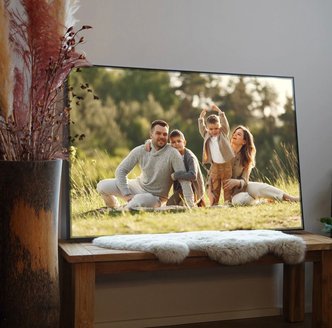 Large framed photograph displayed on wooden table with dried floral arrangement.