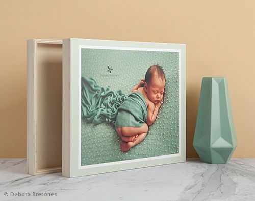 Professional newborn photography displayed in white frame with geometric teal vase.