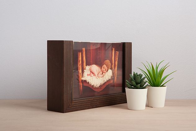 Wooden display box with illuminated photograph and small potted plants beside it.