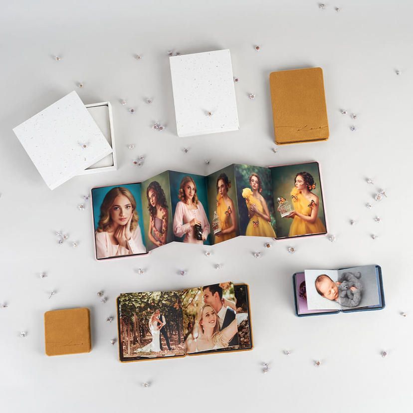 Collection of photo prints and albums displayed on white surface with scattered decorative elements.