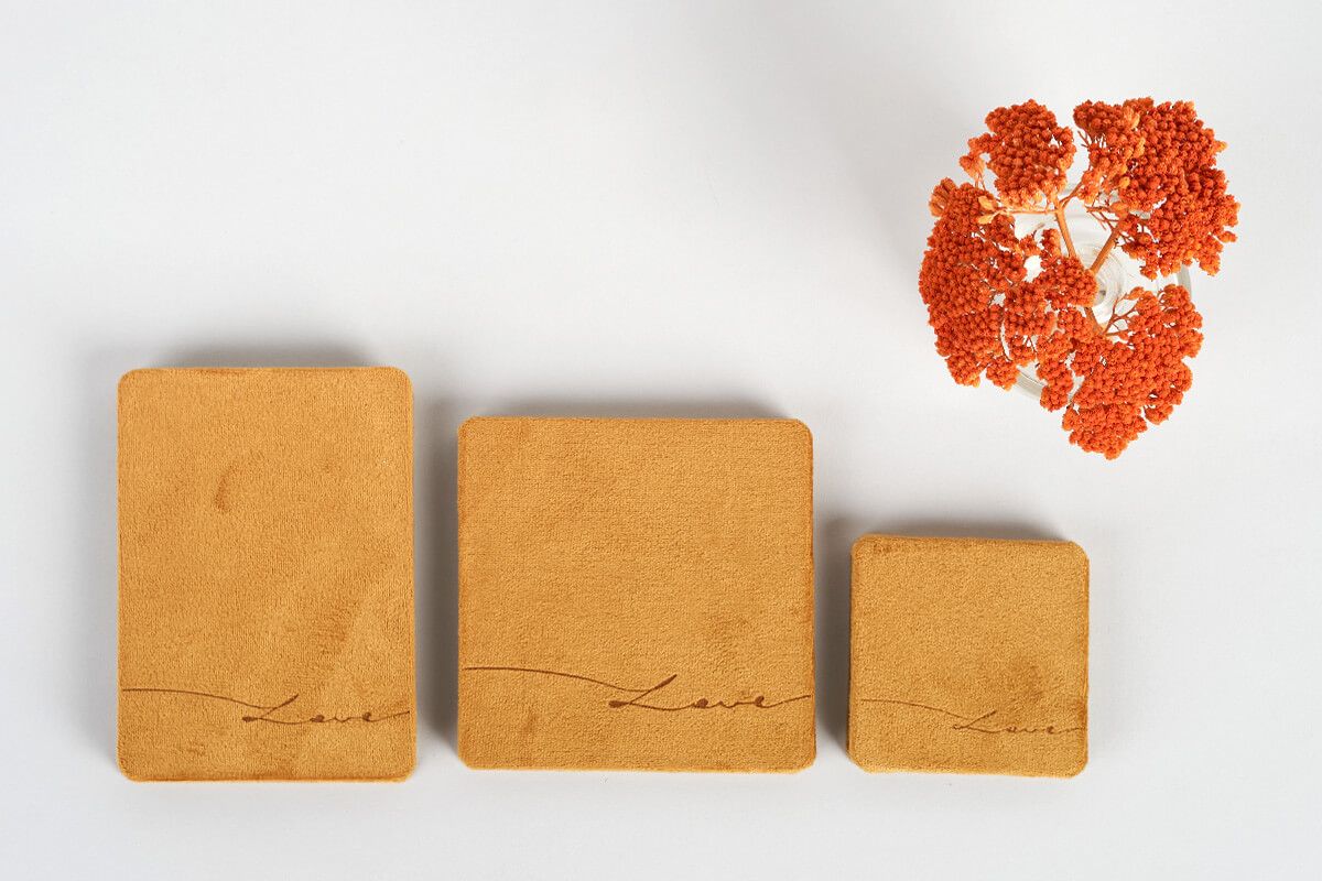 Three brown paper rectangles arranged in descending size with orange dried flowers.