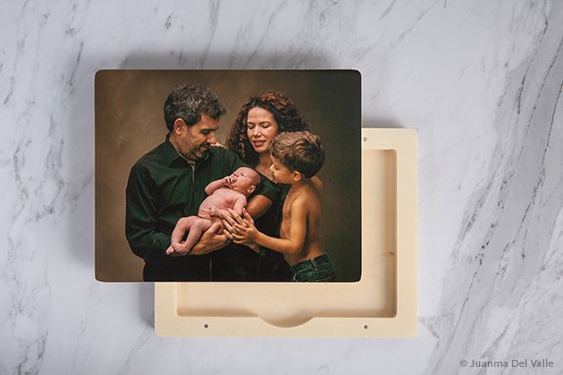 A professional family photo presented in an elegant wooden photo box on marble surface.