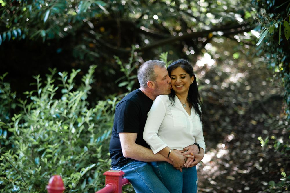 A couple sharing an intimate moment in a garden setting with red accents.