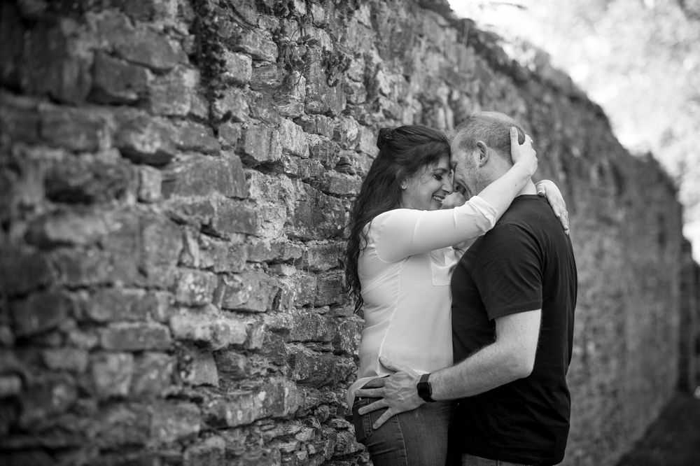 A romantic embrace against an old brick wall in black and white.
