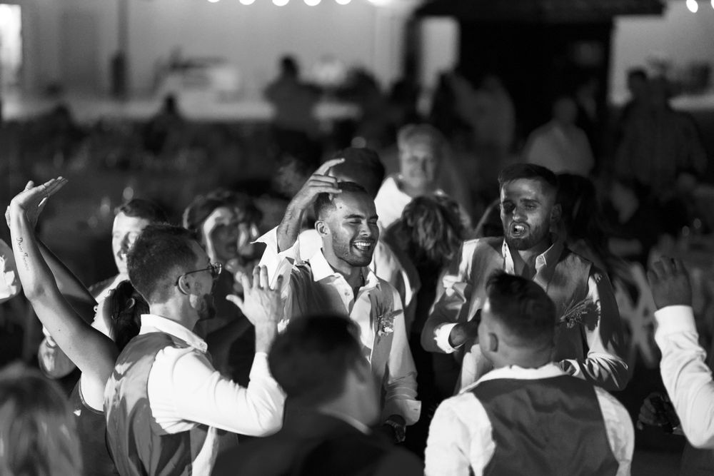 Black and white shot of people dancing and celebrating at a crowded party venue.