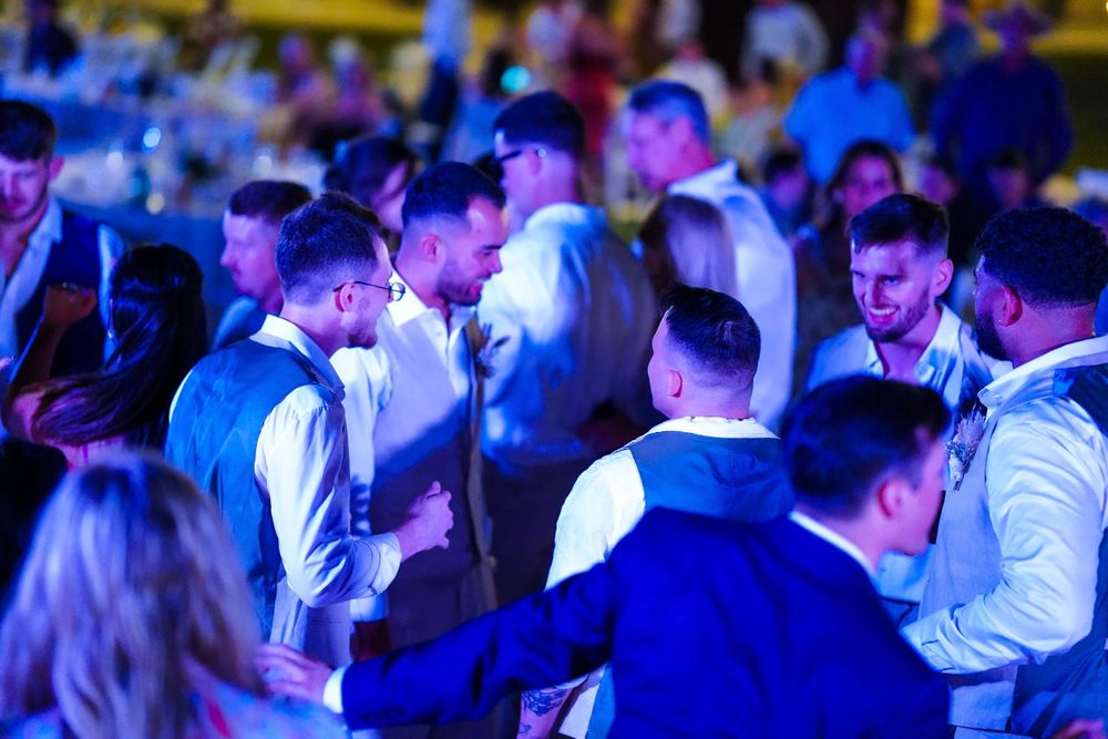 Party crowd illuminated by vibrant blue and purple lighting during a nighttime celebration.