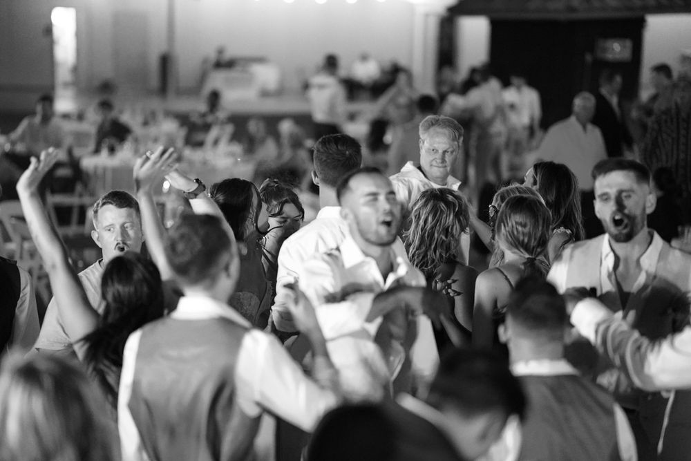 Black and white photo of a crowded dance floor with people celebrating at an energetic party.