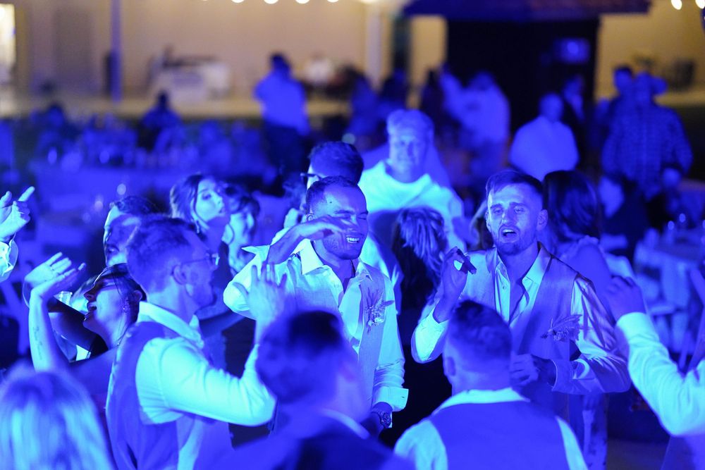 Large group of guests dancing under atmospheric blue lighting at an indoor celebration.