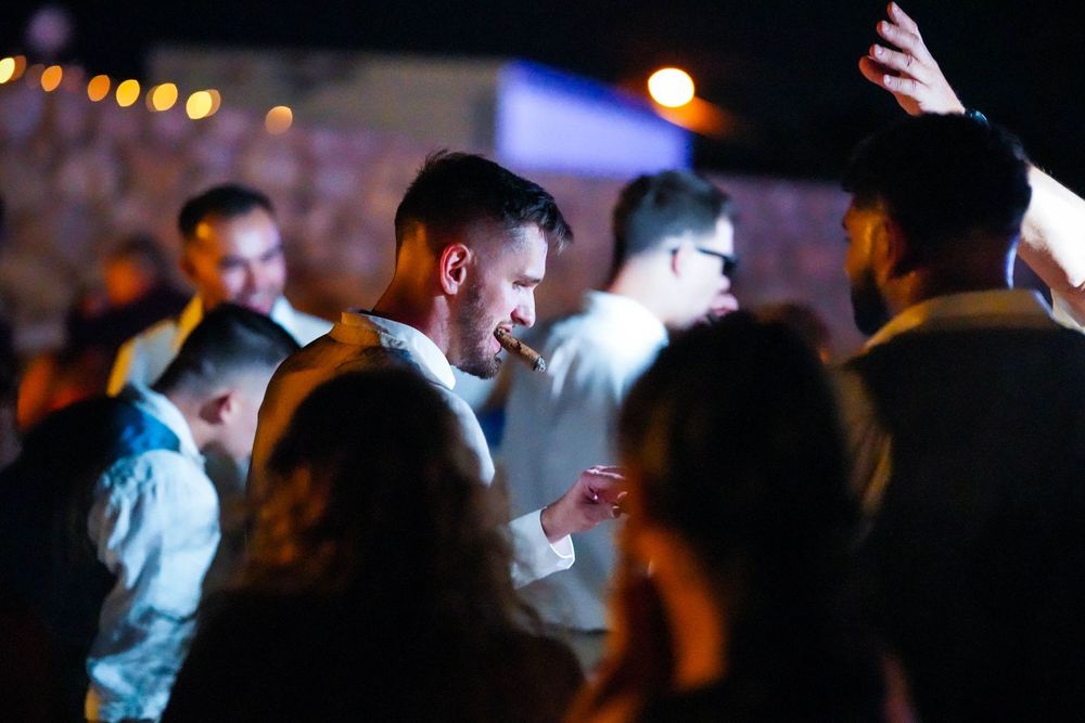 Dark reception venue with dancing guests and bokeh lighting effects.