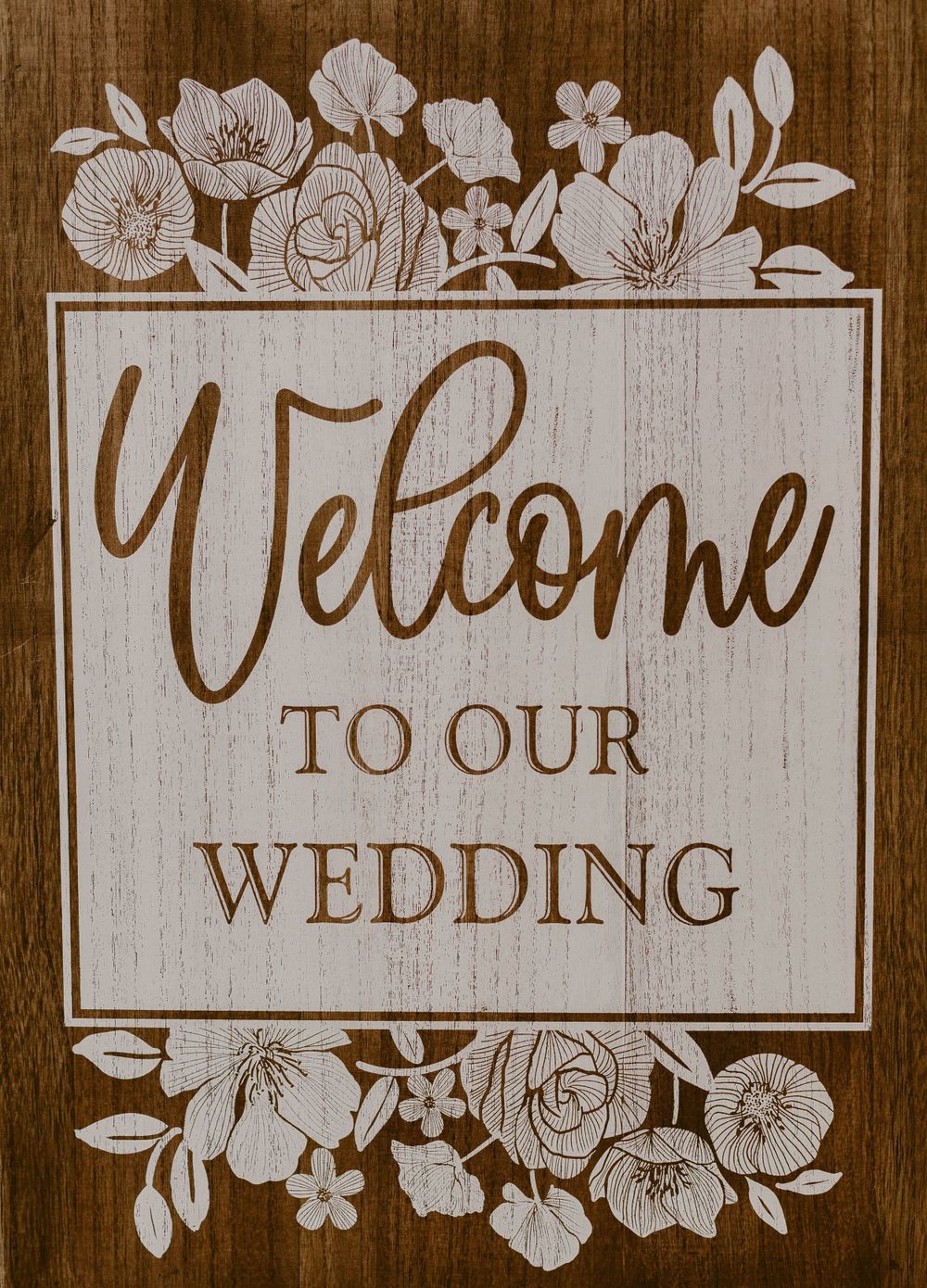 Wooden wedding welcome sign with elegant floral border and script lettering.