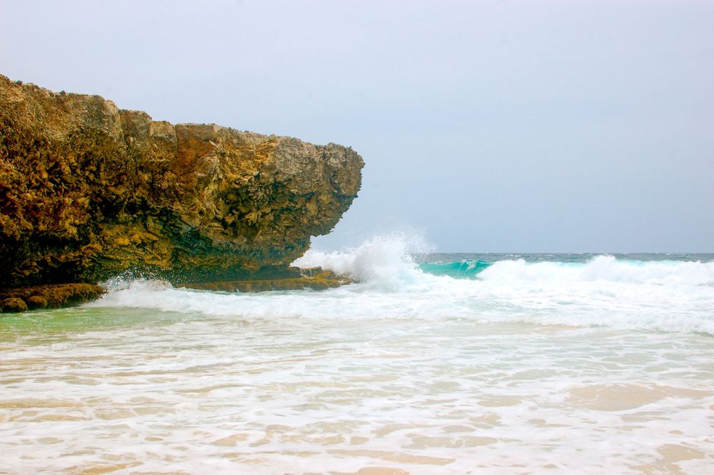 Powerful waves crash against rocky coastal cliffs creating dramatic ocean spray.