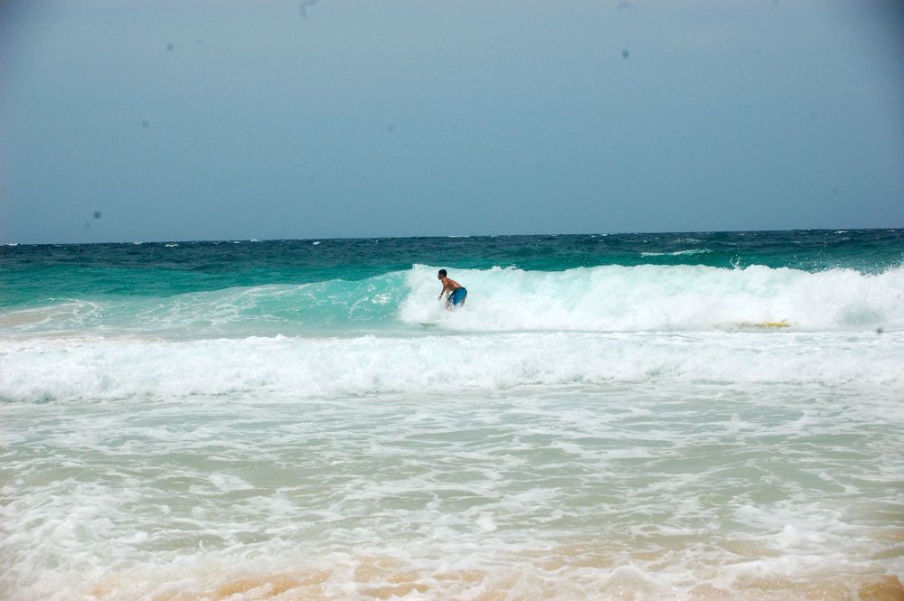 Lone surfer catches a wave in crystal clear turquoise waters.