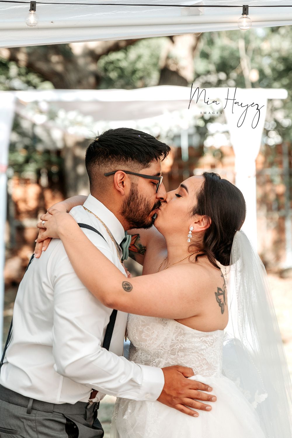 Wedding couple sharing romantic kisses in outdoor setting with natural lighting.