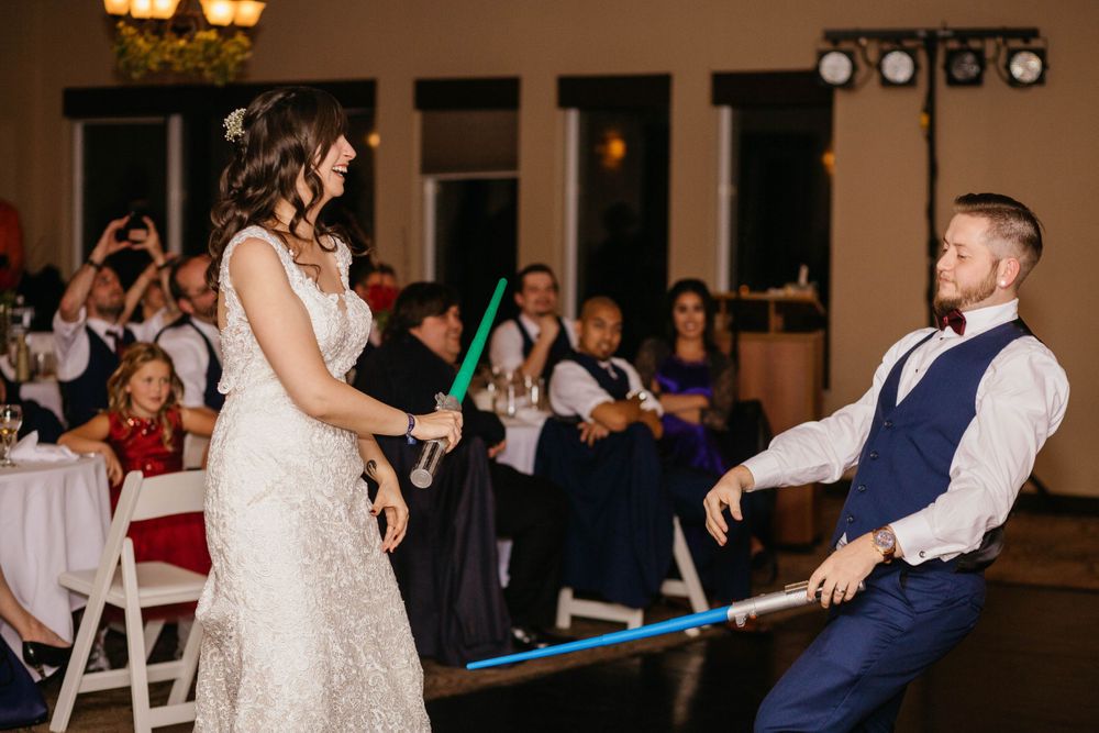Bride and groom enjoying light sabre fight at reception