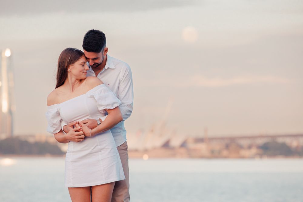 Couple sharing intimate moment on rocky shoreline with Sydney skyline views.