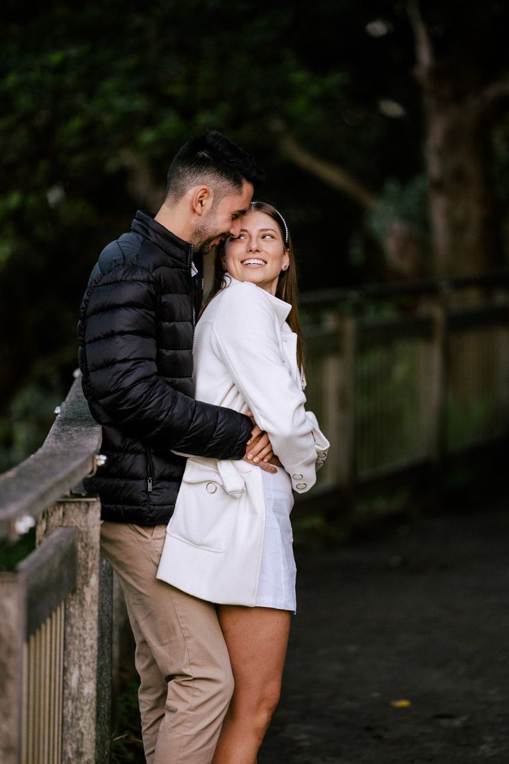 Sweet embrace shared between two people on a wooden railing outdoors.