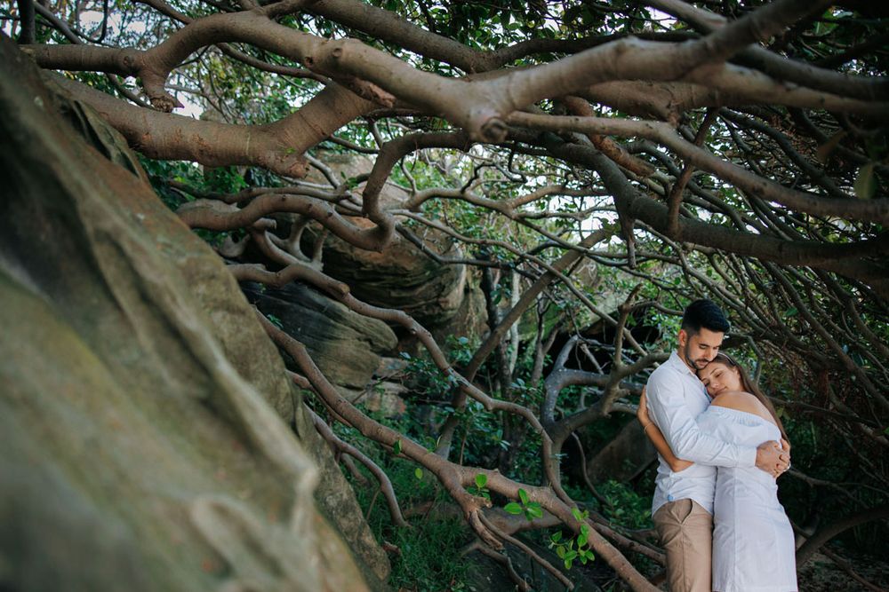 Intimate moment captured under natural tree canopy by the water.