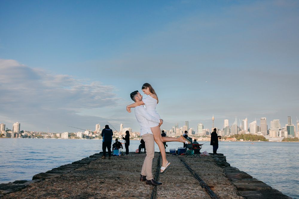 Waterfront engagement photography session with Sydney skyline as backdrop.