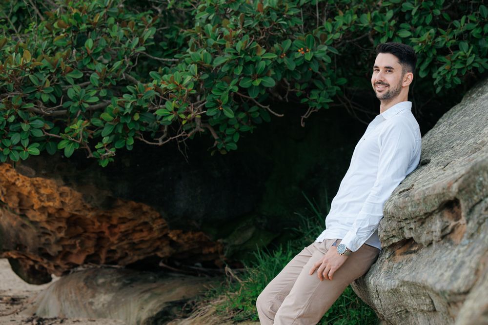 Romantic coastal photoshoot among natural rock formations and greenery.