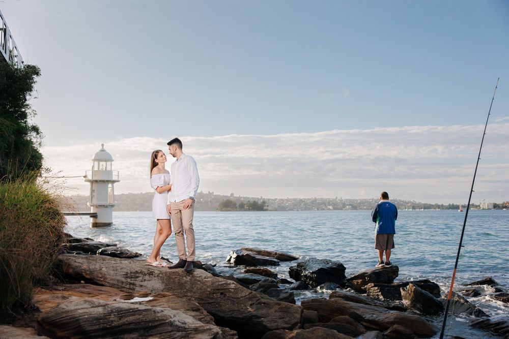 Seaside engagement session with lighthouse and harbor views.