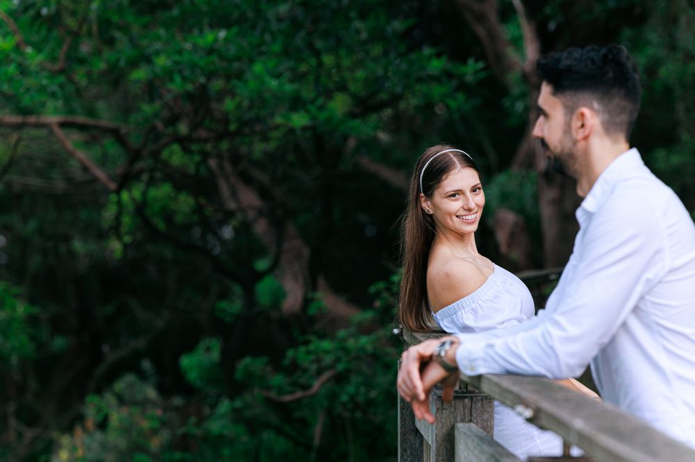 A couple in white outfits shares playful moments in a garden setting.