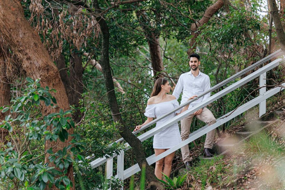 A couple shares romantic moments along a wooded pathway.