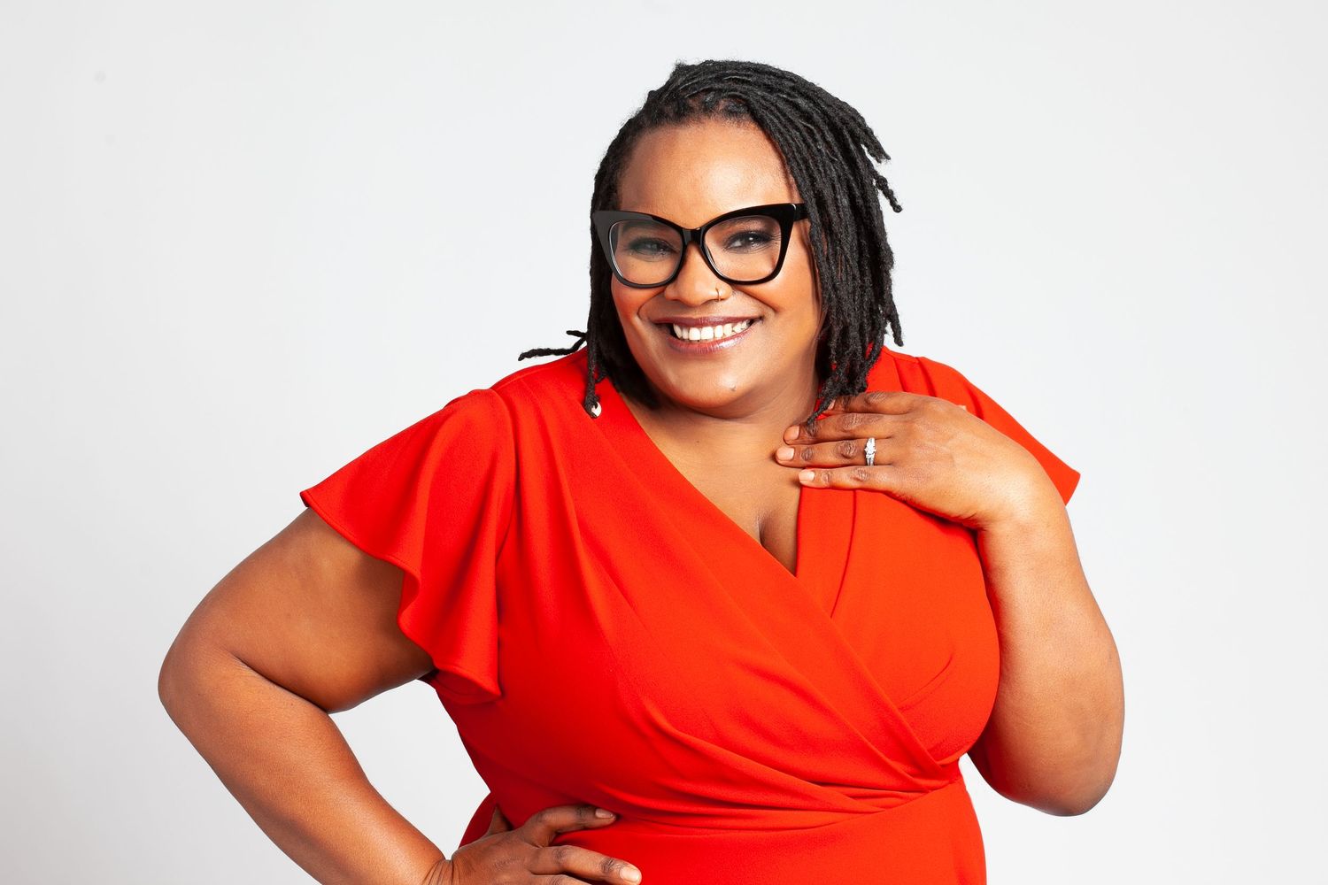 Dr. Joy's headshot to promote her new book. She's wearing a red dress and black glasses.