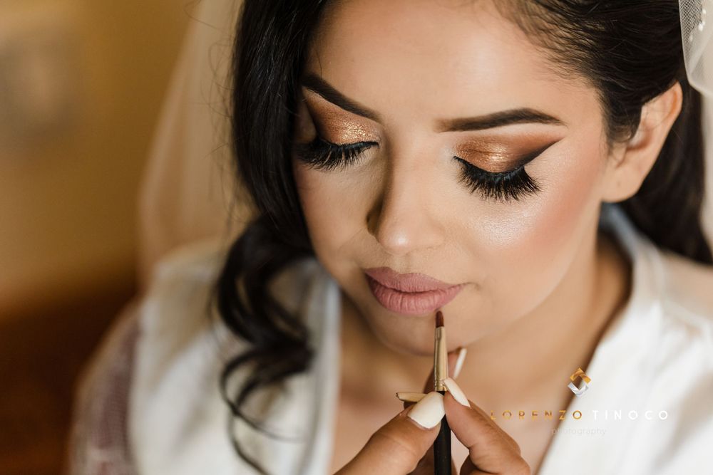 Close-up of glamorous bridal makeup application with dramatic winged eyeliner and pink lips.
