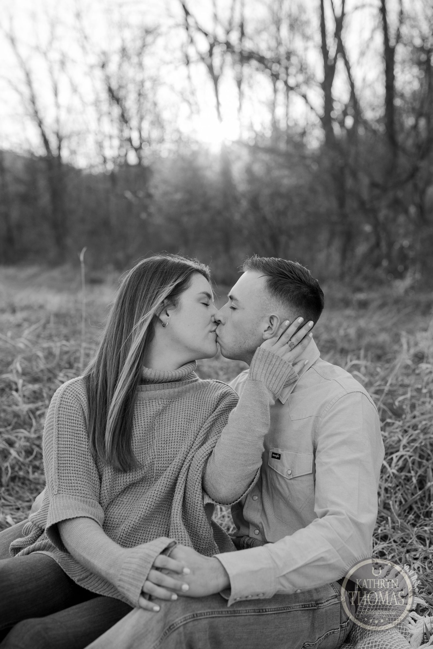 A black and white portrait captures an intimate moment between a couple in a natural outdoor setting.
