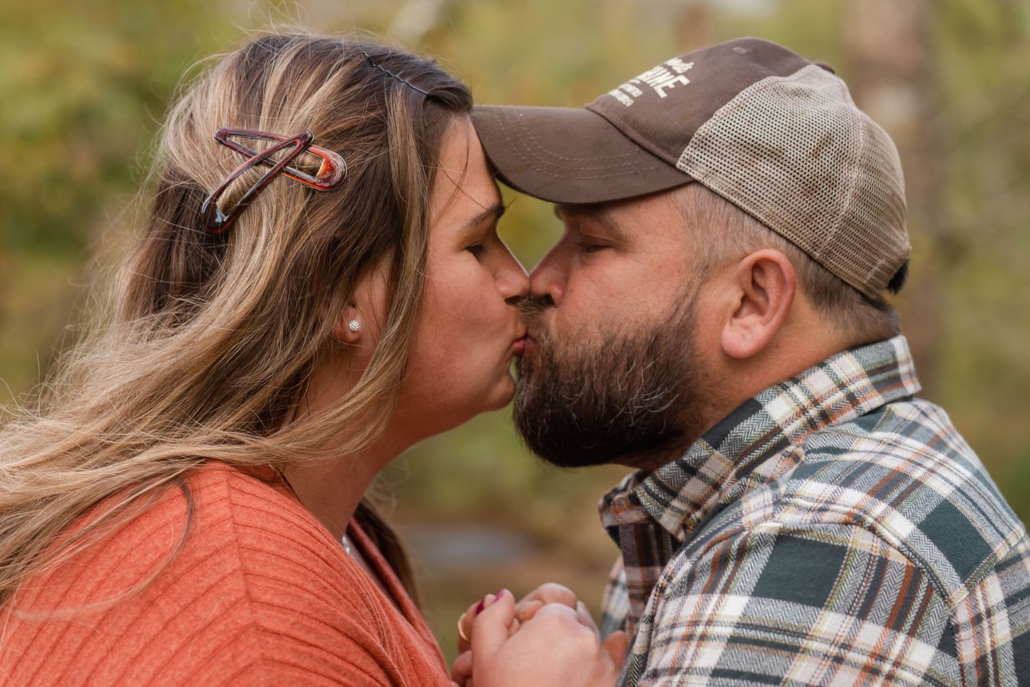 Intimate autumn portrait session with plaid shirt and orange sweater against fall foliage.