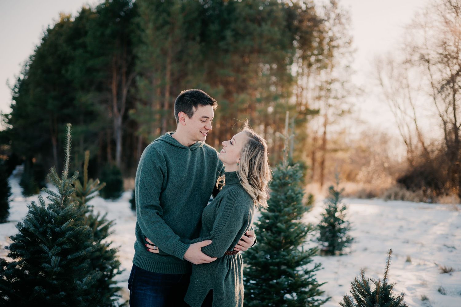 Couple sharing romantic moment in winter forest setting with snow and evergreens.