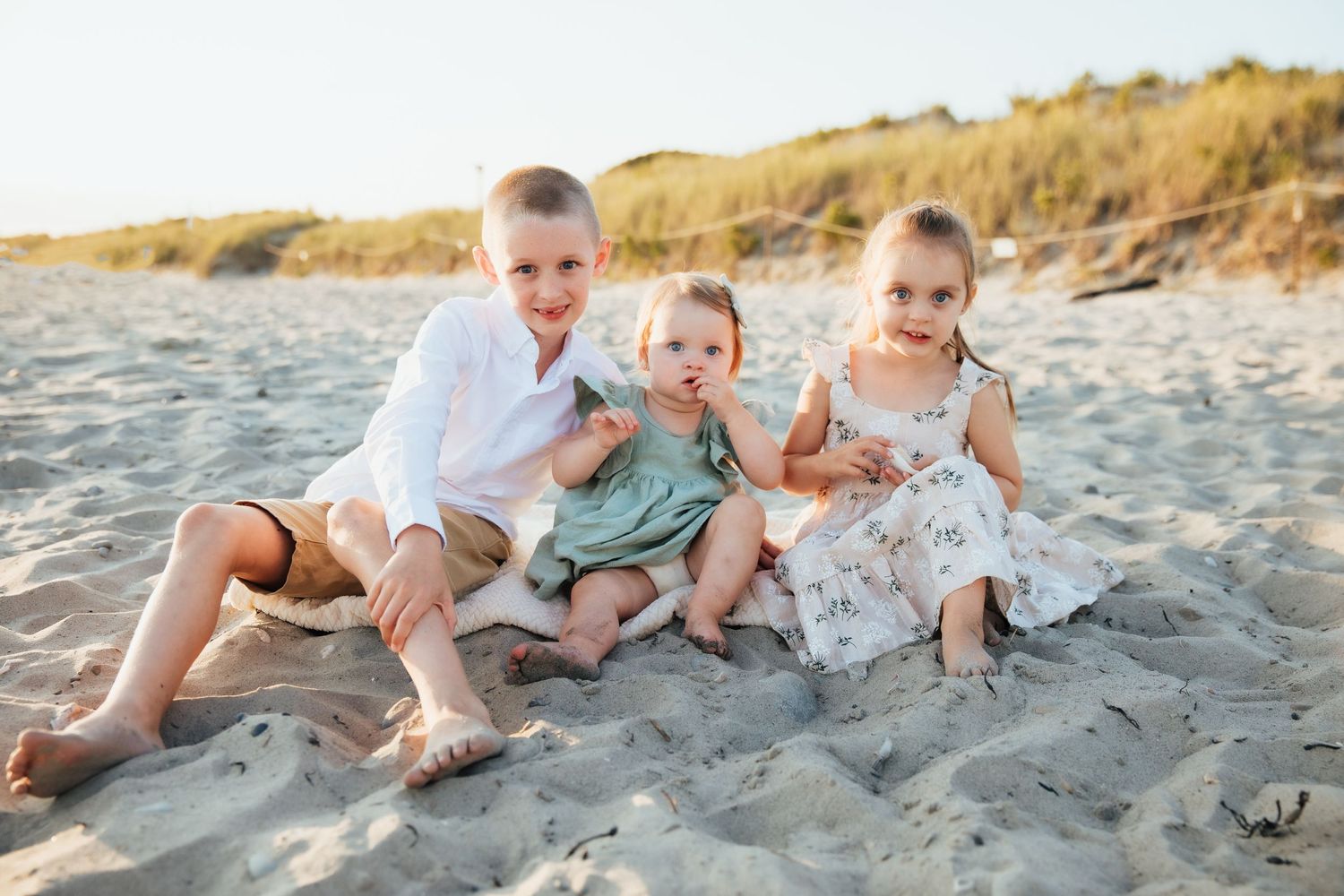 Three siblings sitting together on sandy beach at sunset. second beach Middletown Rhode Island
