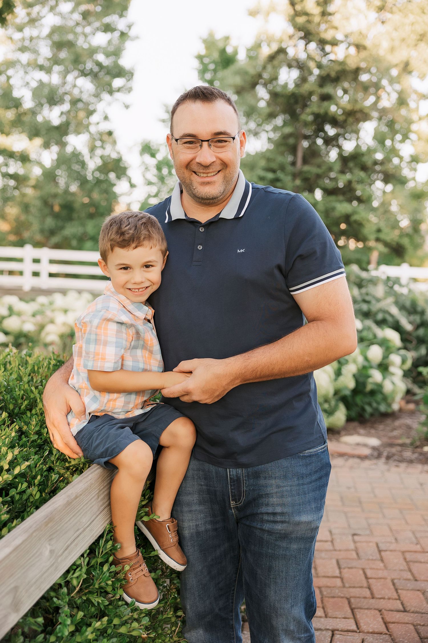 Parent and child share a sweet moment on a brick pathway in a garden setting.