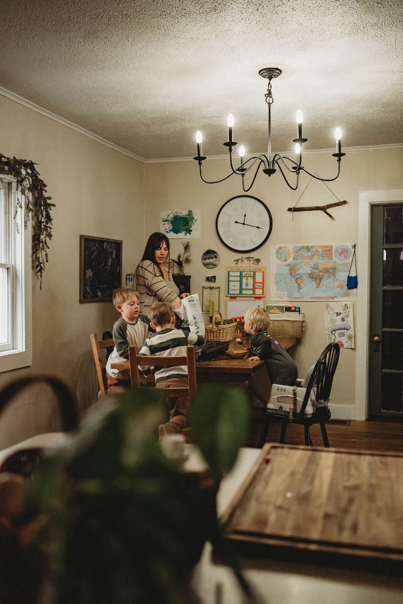 Homeschool room with chandelier, maps, and wooden furniture in warm evening light.