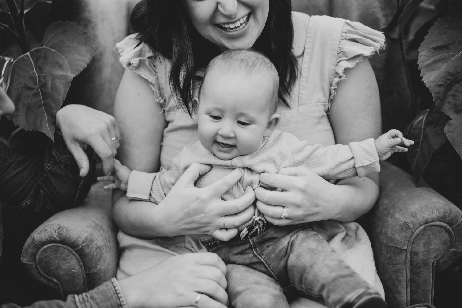 A joyful moment captured between parent and baby sitting in a cozy armchair.