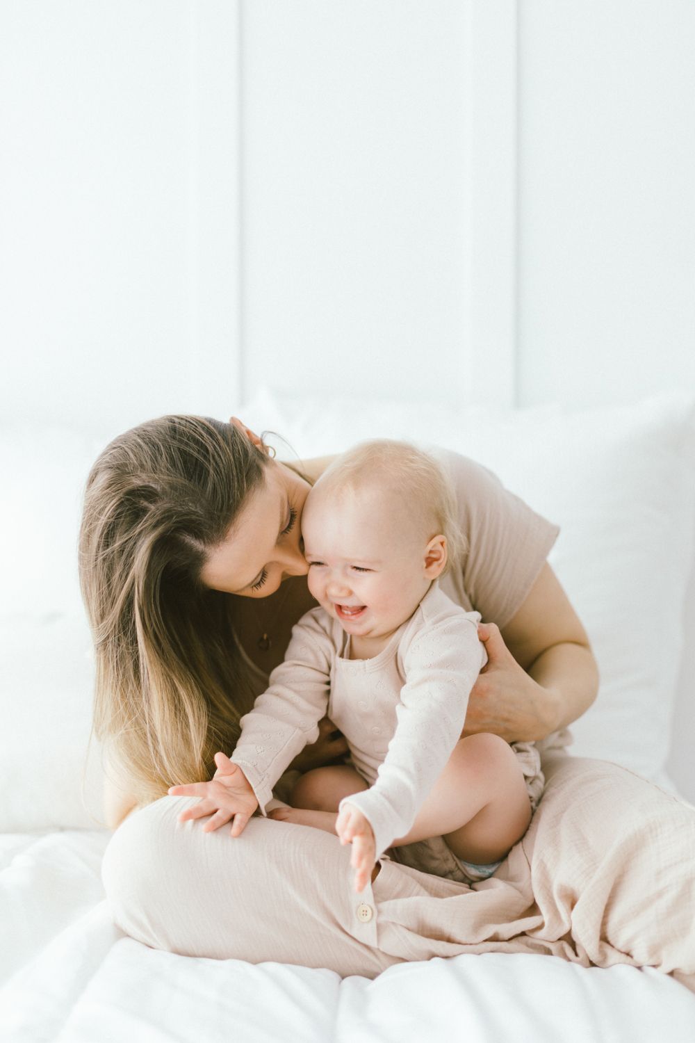 Gentle embrace captured in soft natural light against white backdrop.