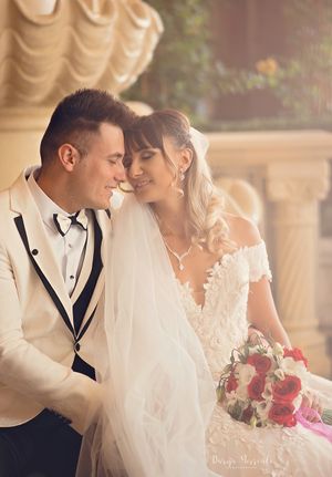 A romantic wedding portrait of a couple sharing an intimate moment near ornate architecture.