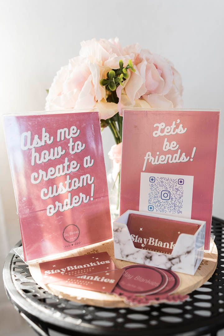 Pink marketing display with QR code and custom order signs next to pale roses.