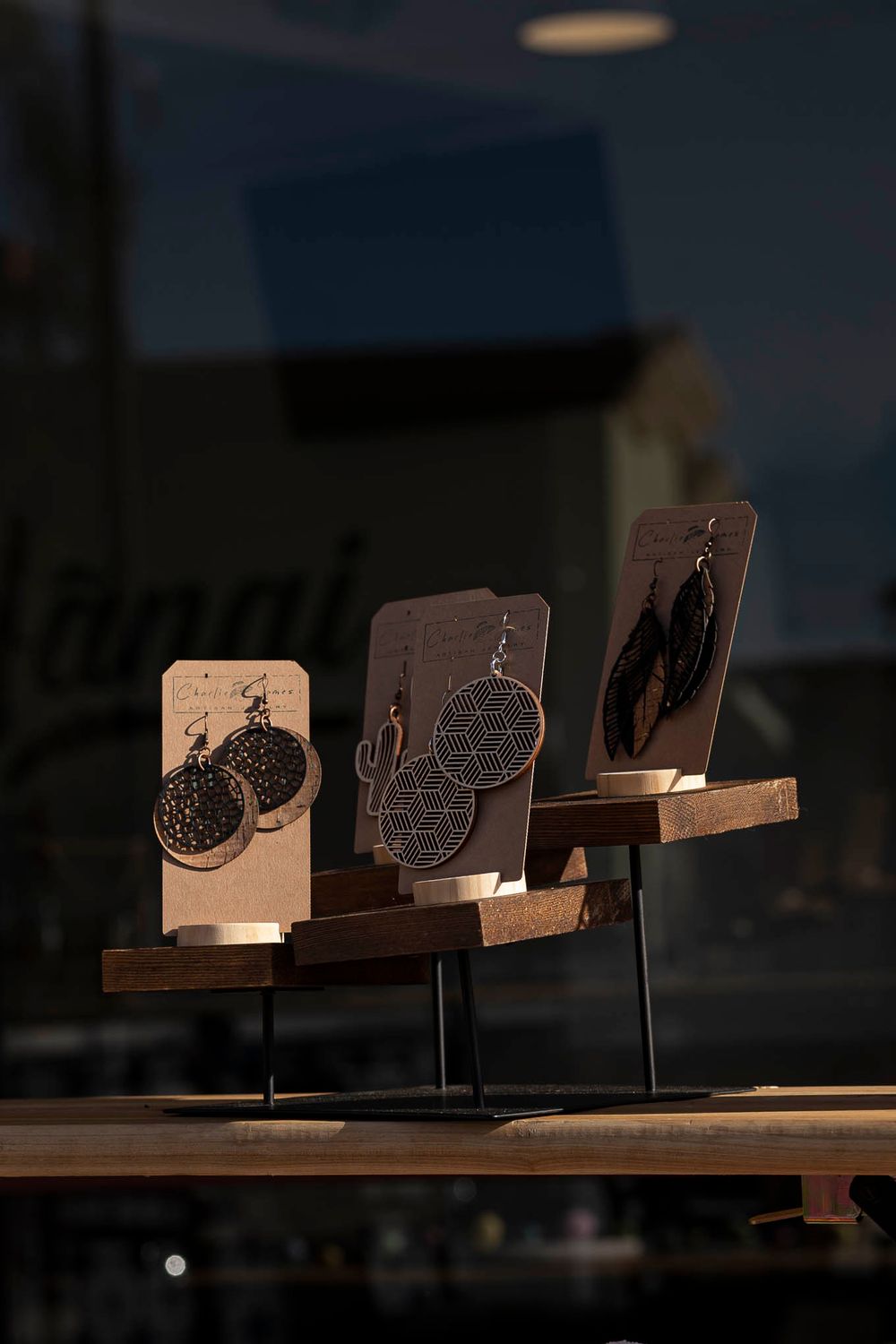 Wooden display stands showcasing artisanal earrings with circular designs in dramatic lighting.