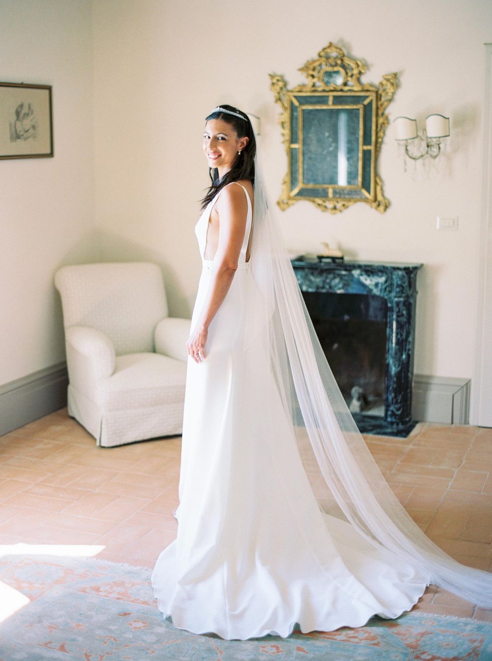 A bride in a white dress standing in front of a fireplace at La Foce.